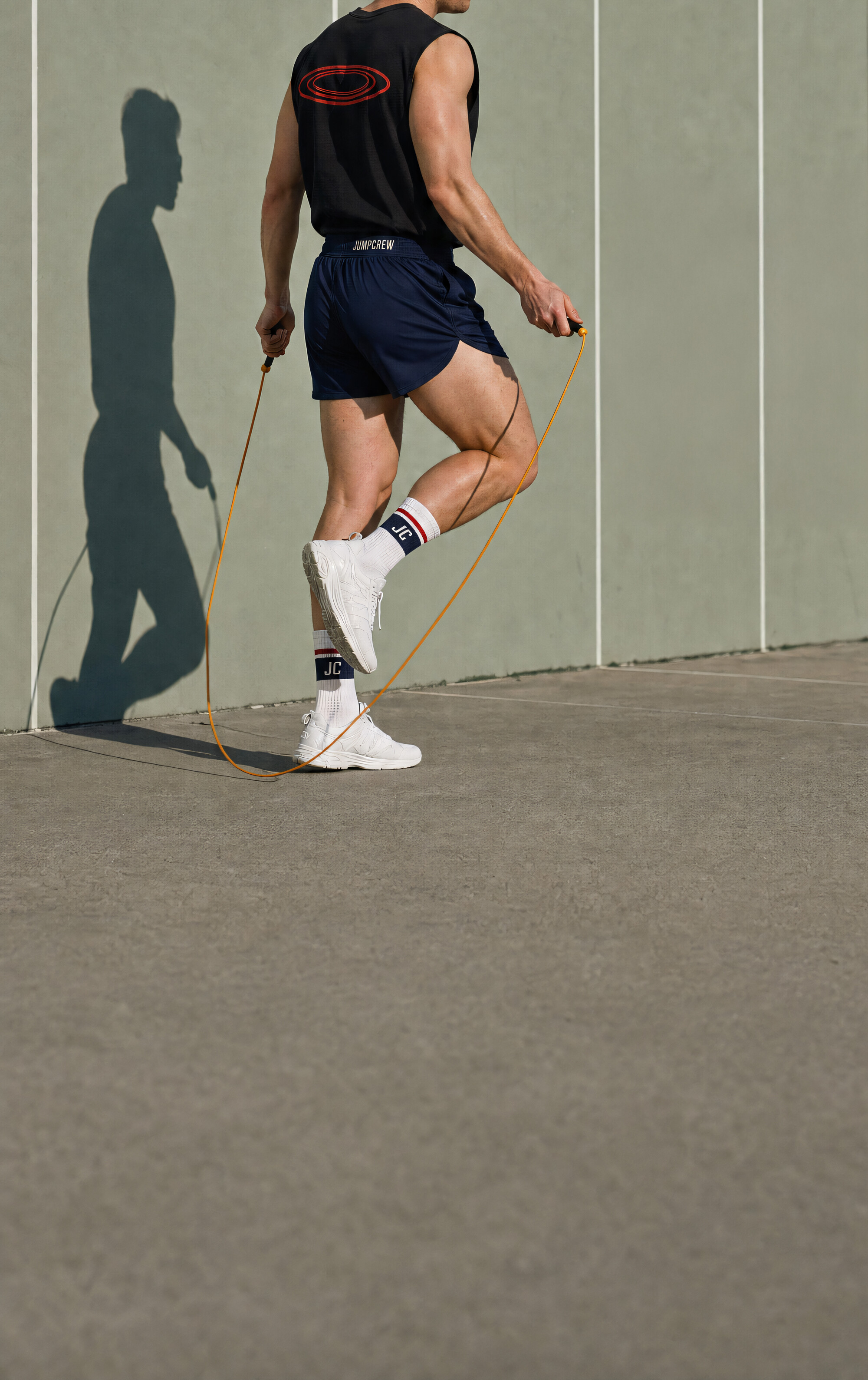 JUMPCREW athlete wearing the tank, shorts and socks, mid jump on the sidewalk